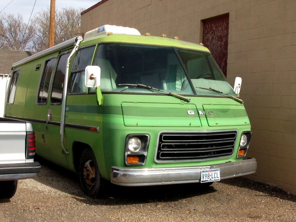 A green motorhome parked outdoors with its roof exposed to sun and weather