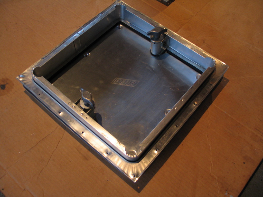 A roof vent frame installed into a cut opening in an RV roof, insulation visible at the edges
