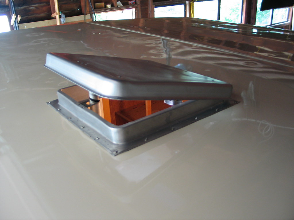 An open vent cutout in an RV's aluminum roof with wiring visible inside
