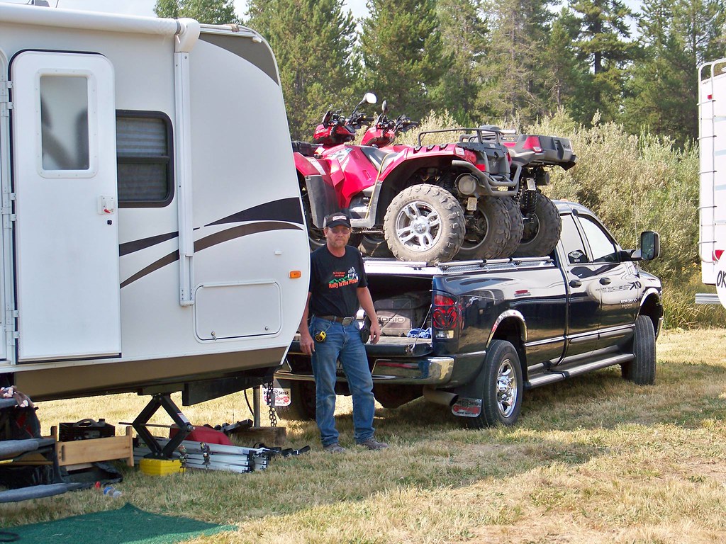 A travel trailer parked at a campsite, its fiberglass sidewall exposed to sun and moisture