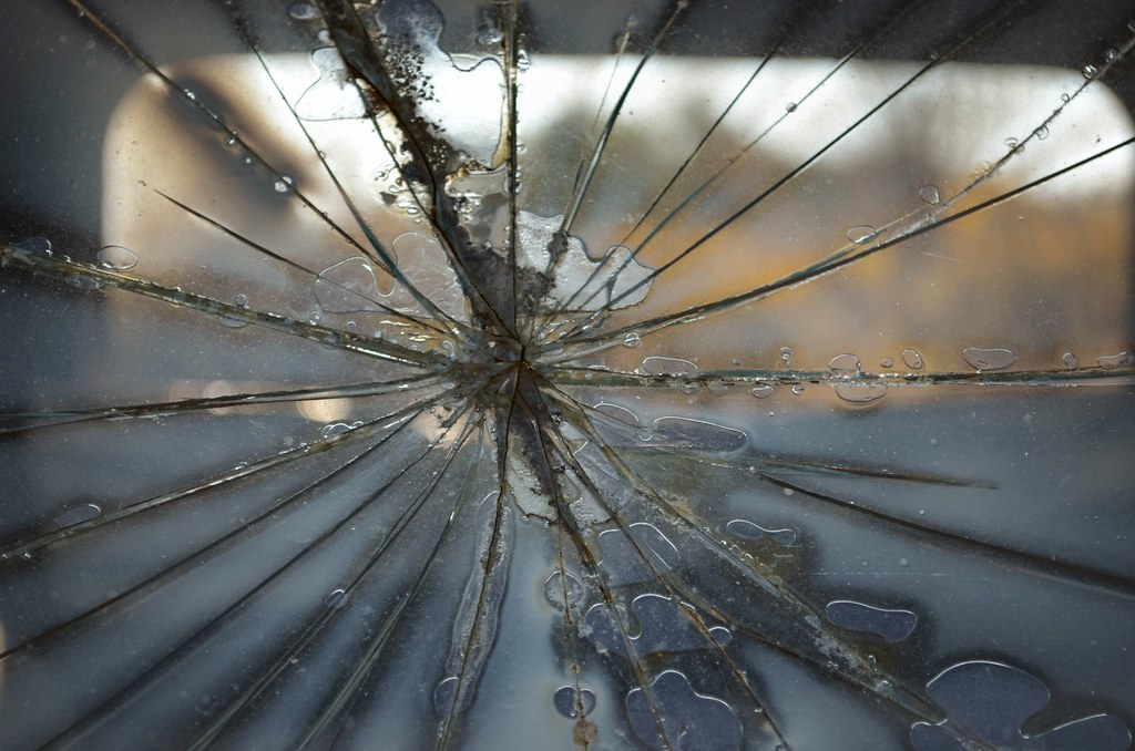Close-up of a spiderweb crack radiating across a windshield after a rock-strike impact