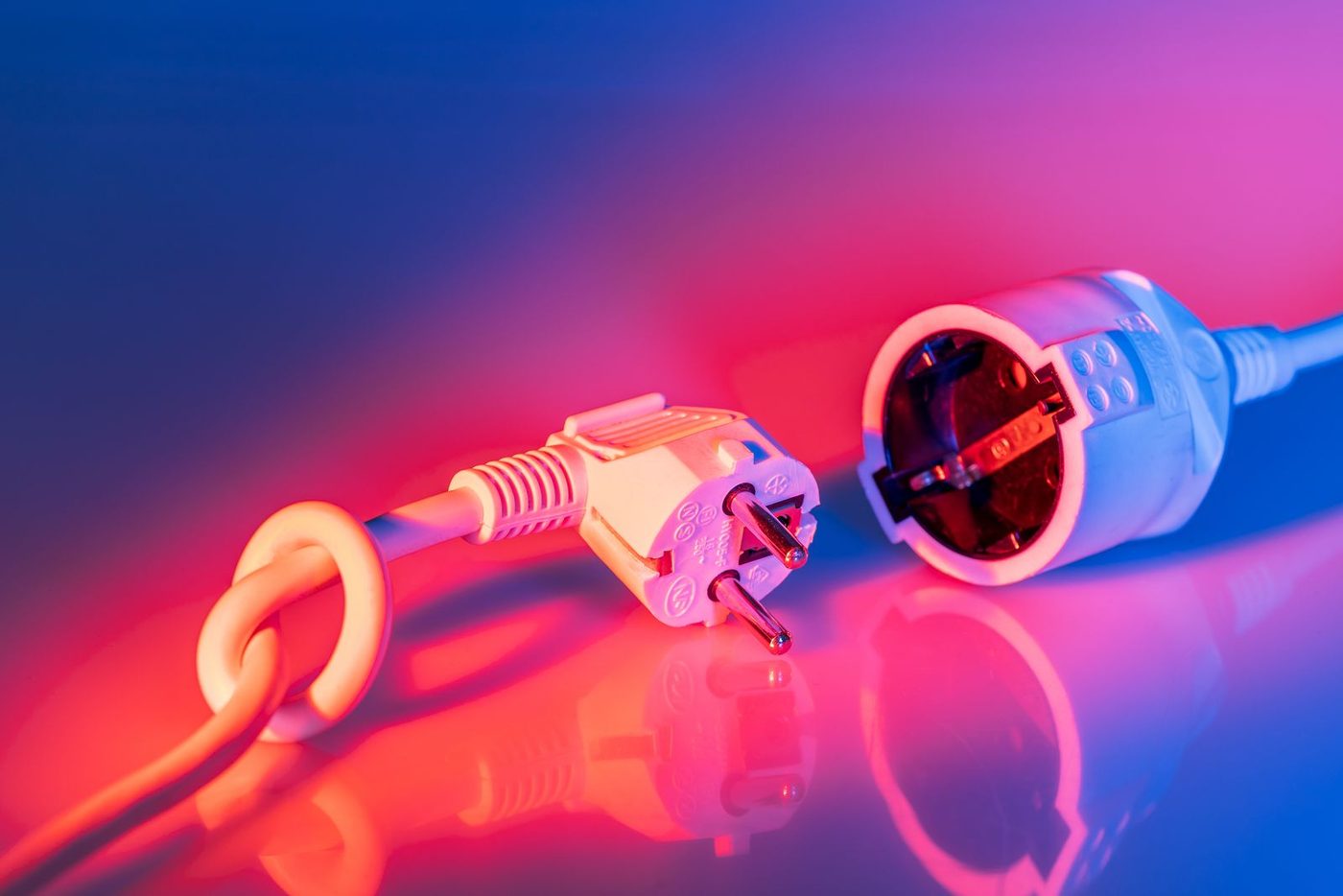 A close-up of an electrical plug and outlet with dramatic lighting