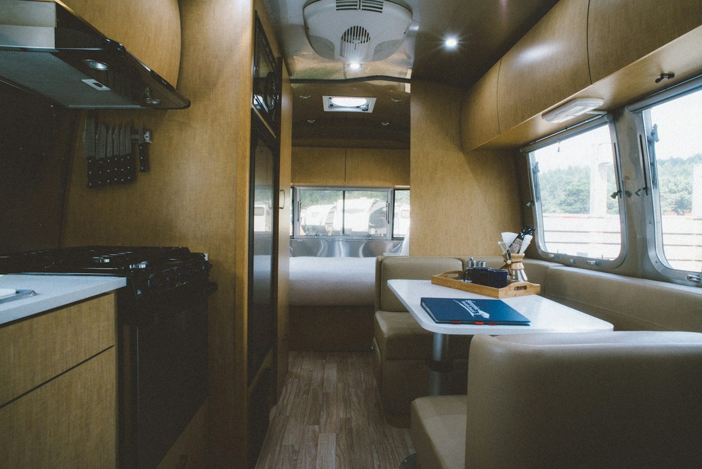 A remodeled Airstream trailer interior with wood paneling, a dinette, and a kitchen counter