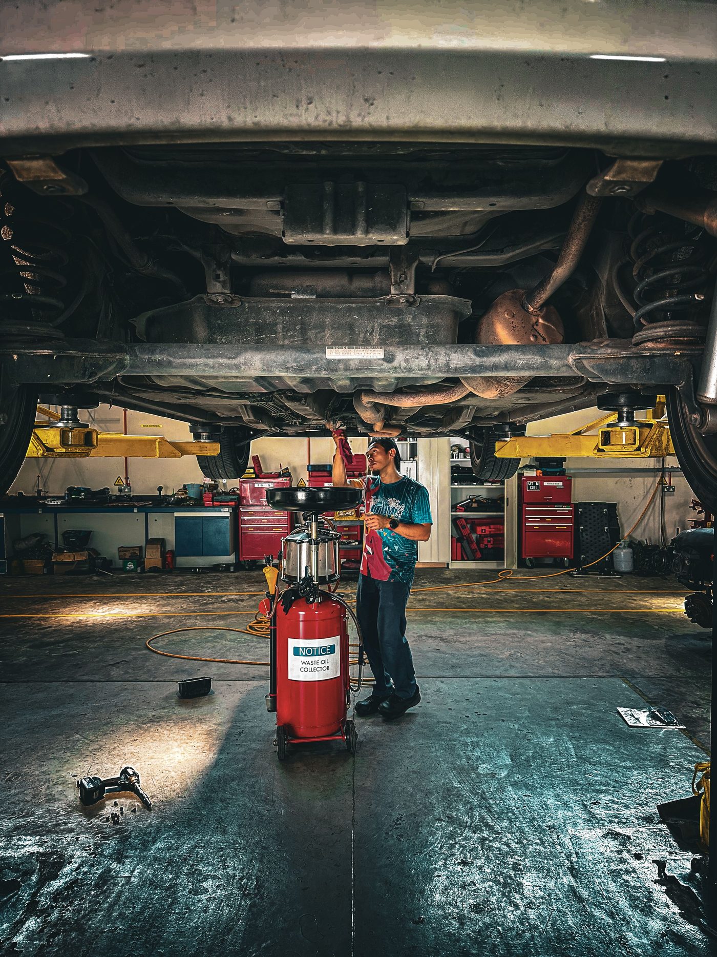 A mechanic inspecting the underside of a vehicle on a lift in a repair shop