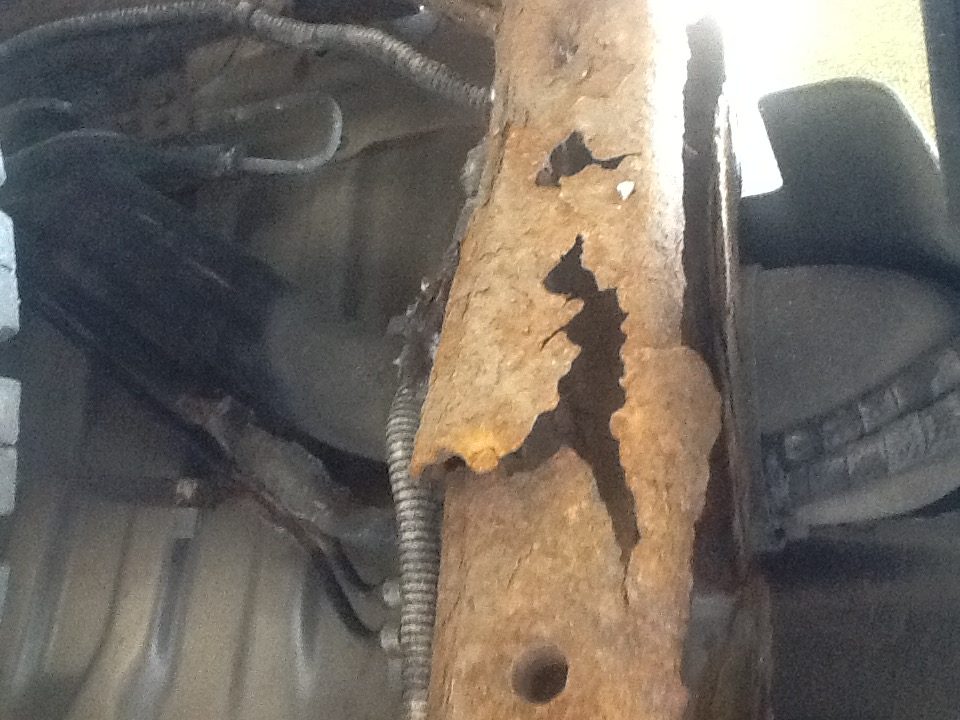 Close-up of a rusted vehicle frame member showing heavy surface corrosion