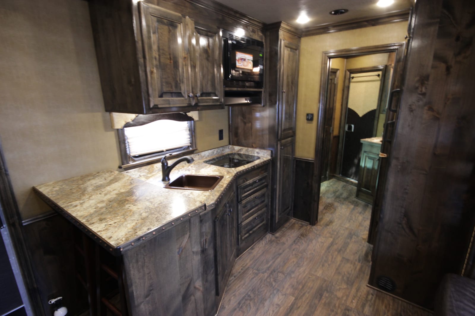 RV kitchen galley with sink, cooktop, and overhead microwave cabinet