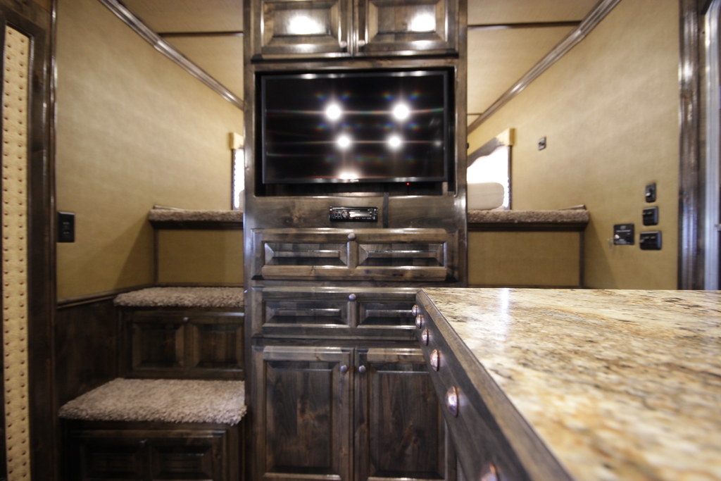 An RV kitchen with refrigerator, stove, and overhead cabinets