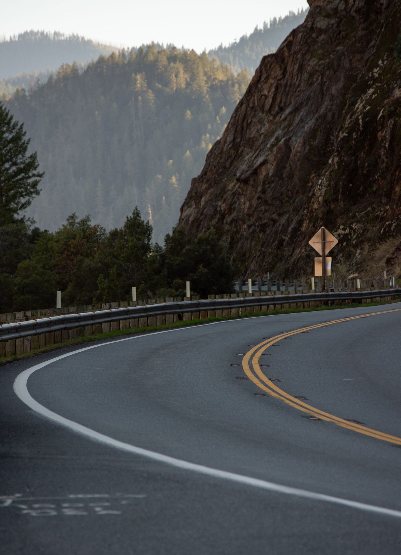 A winding two-lane mountain road descending through a rocky canyon