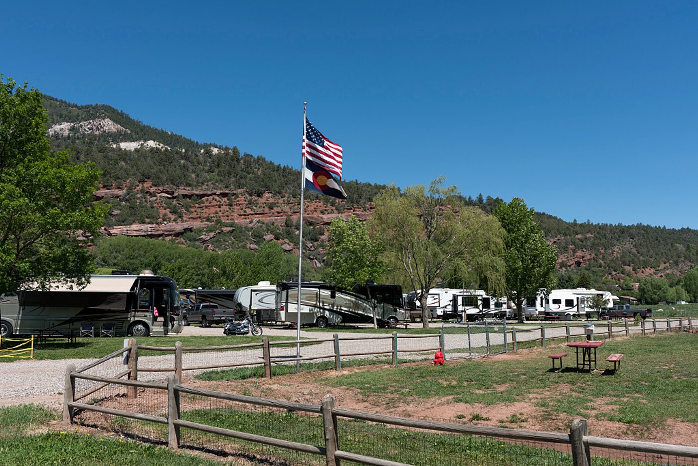 Several RVs and travel trailers parked at a campground with mountains in the background