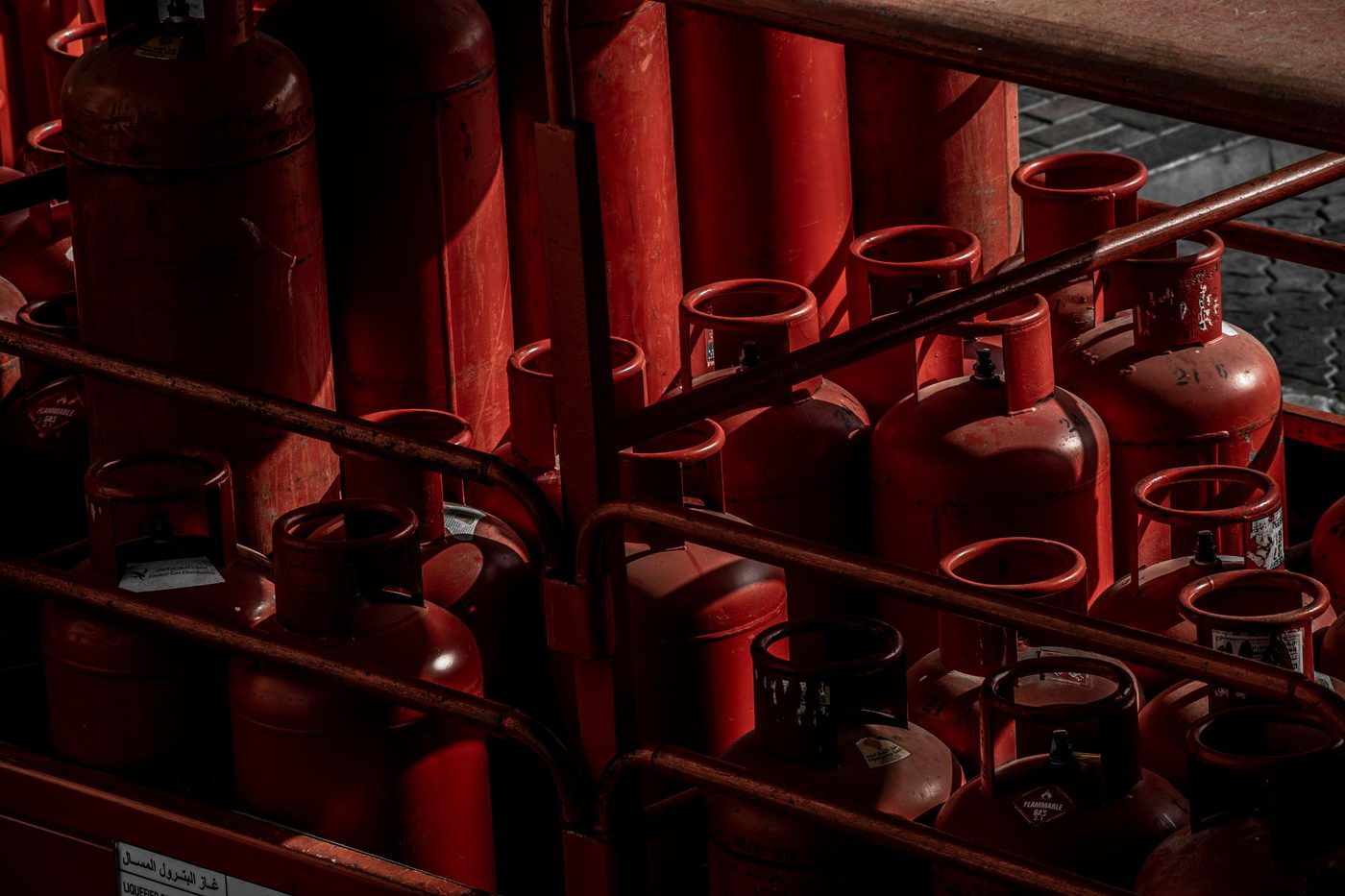A row of red gas cylinders stored together in an outdoor storage cage