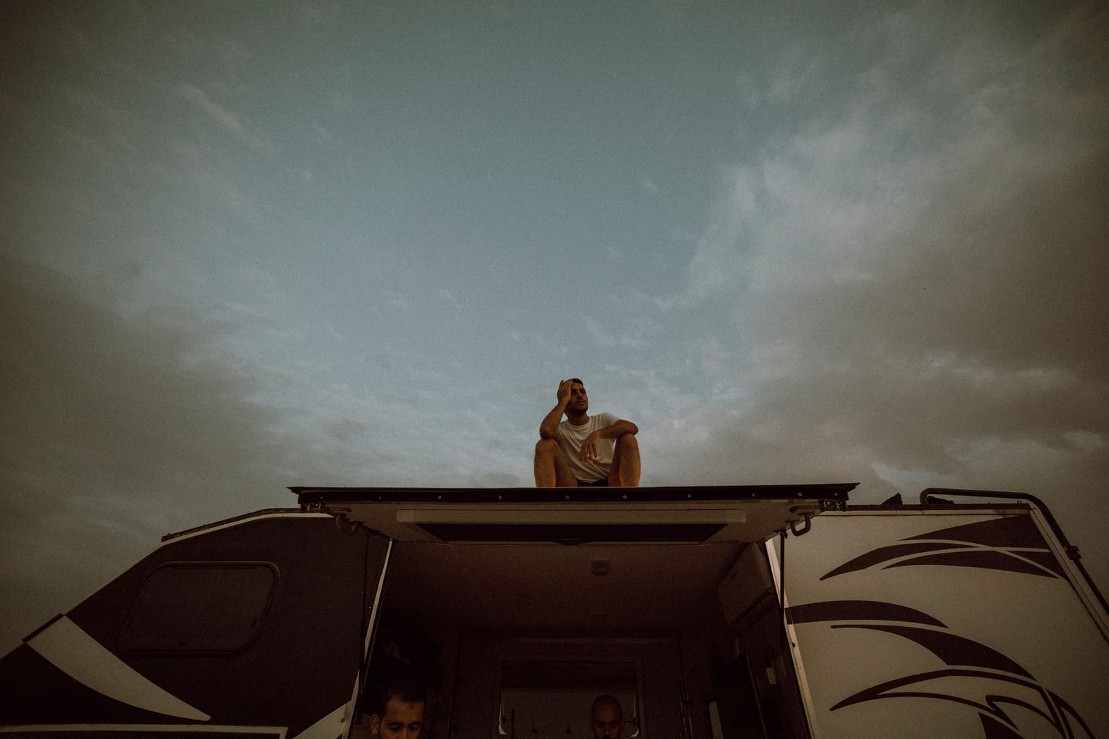 A person sitting on an RV's rooftop overlooking a desert landscape