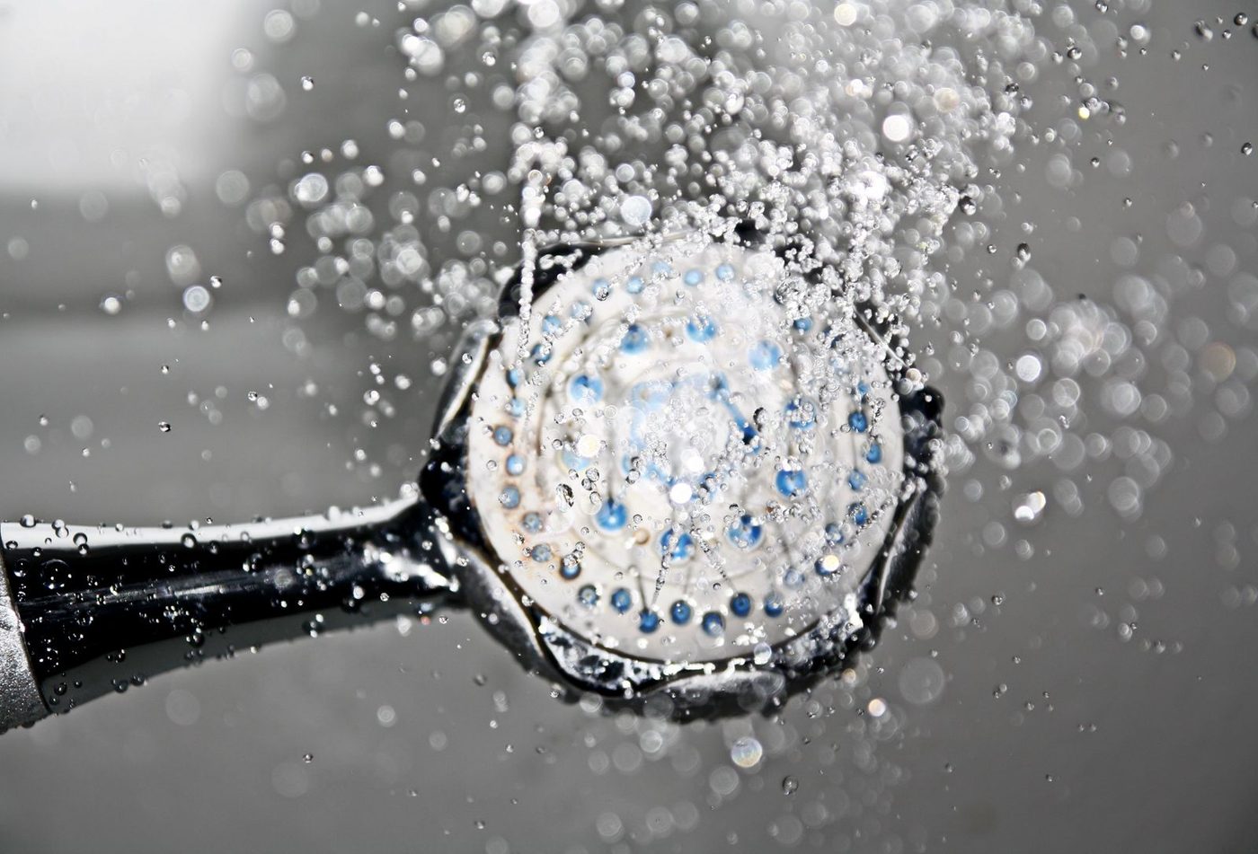 A black shower head with water running