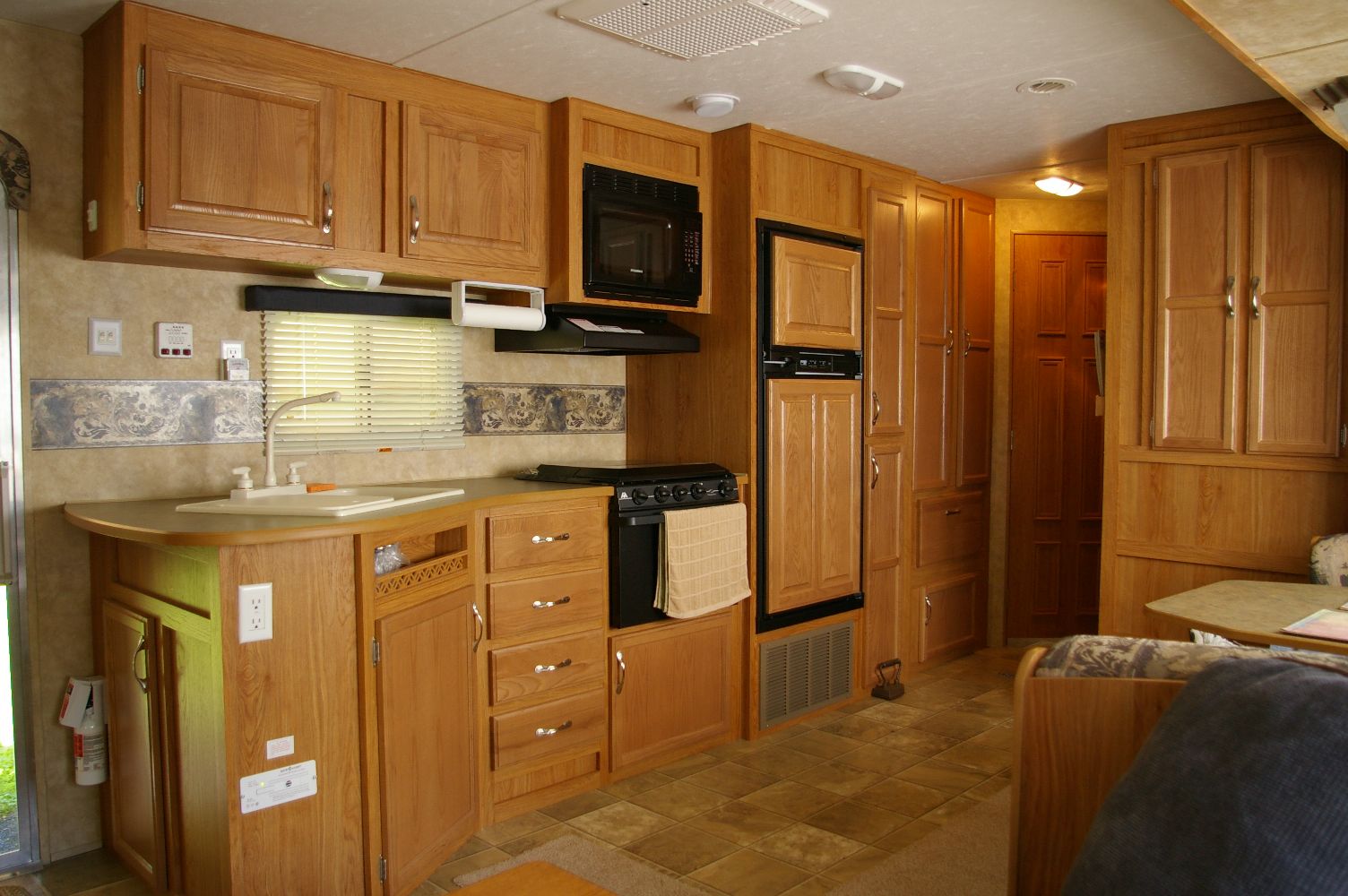 RV kitchen slide-out with cabinetry, microwave, and refrigerator