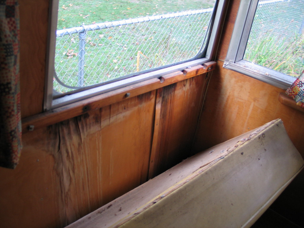 Interior view of an RV window frame with aluminum trim looking toward a yard