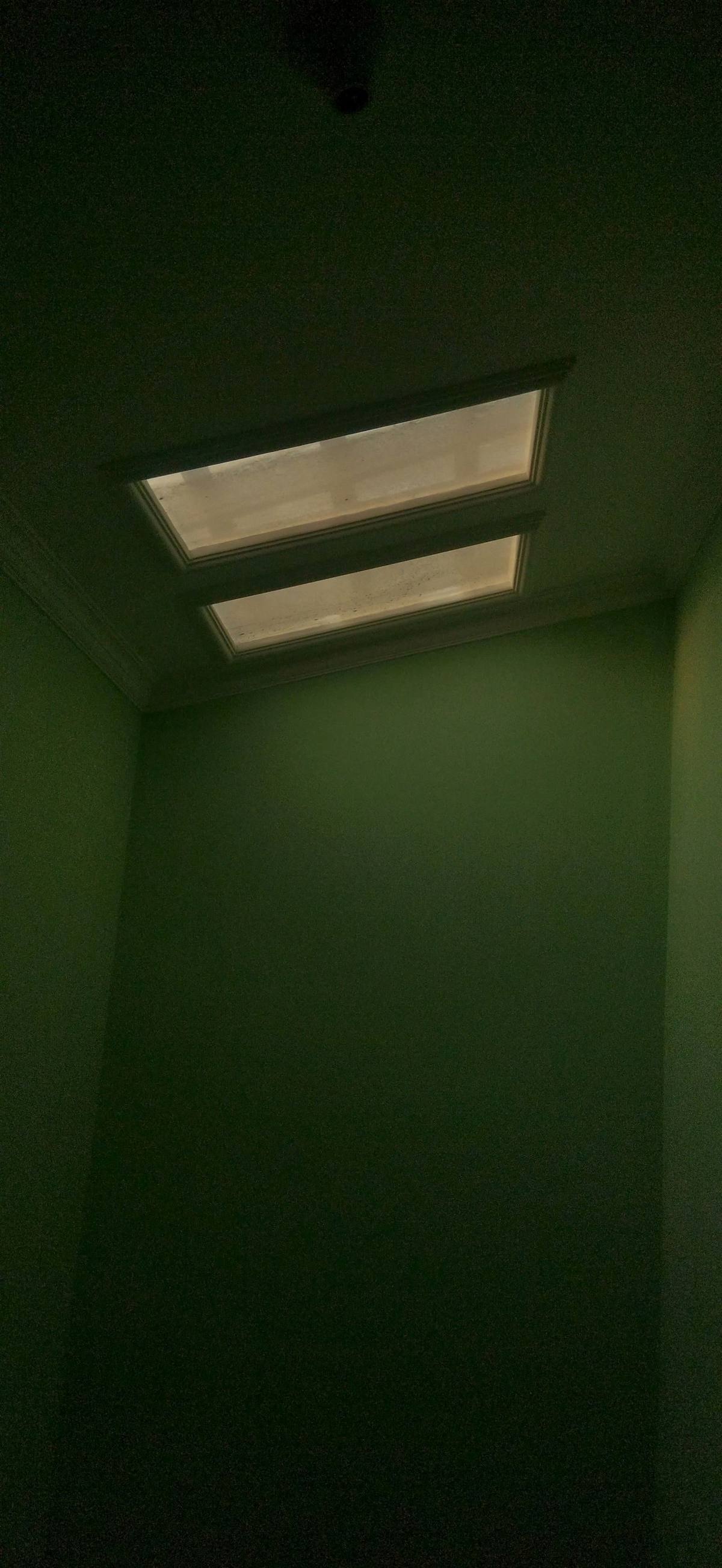 An empty room lit by daylight streaming through an overhead skylight