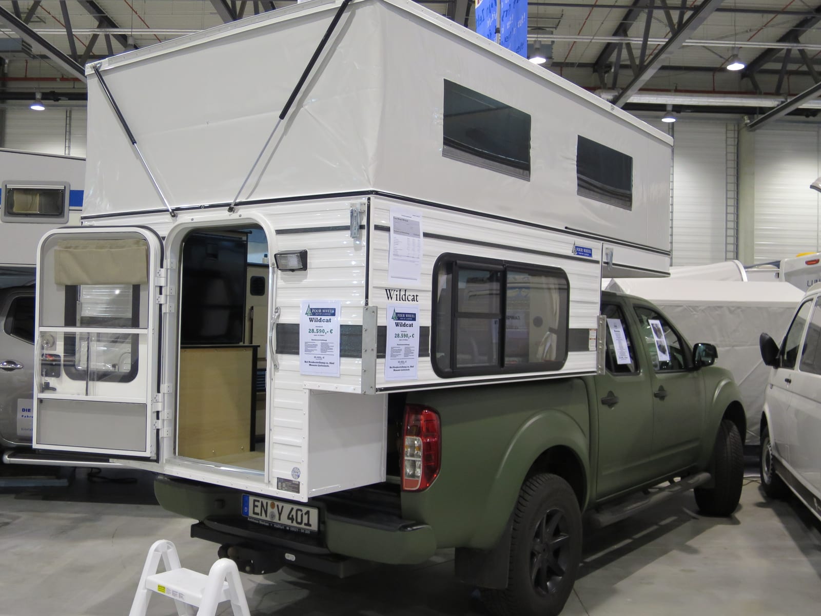 A truck camper with its slide-out room extended at a campsite