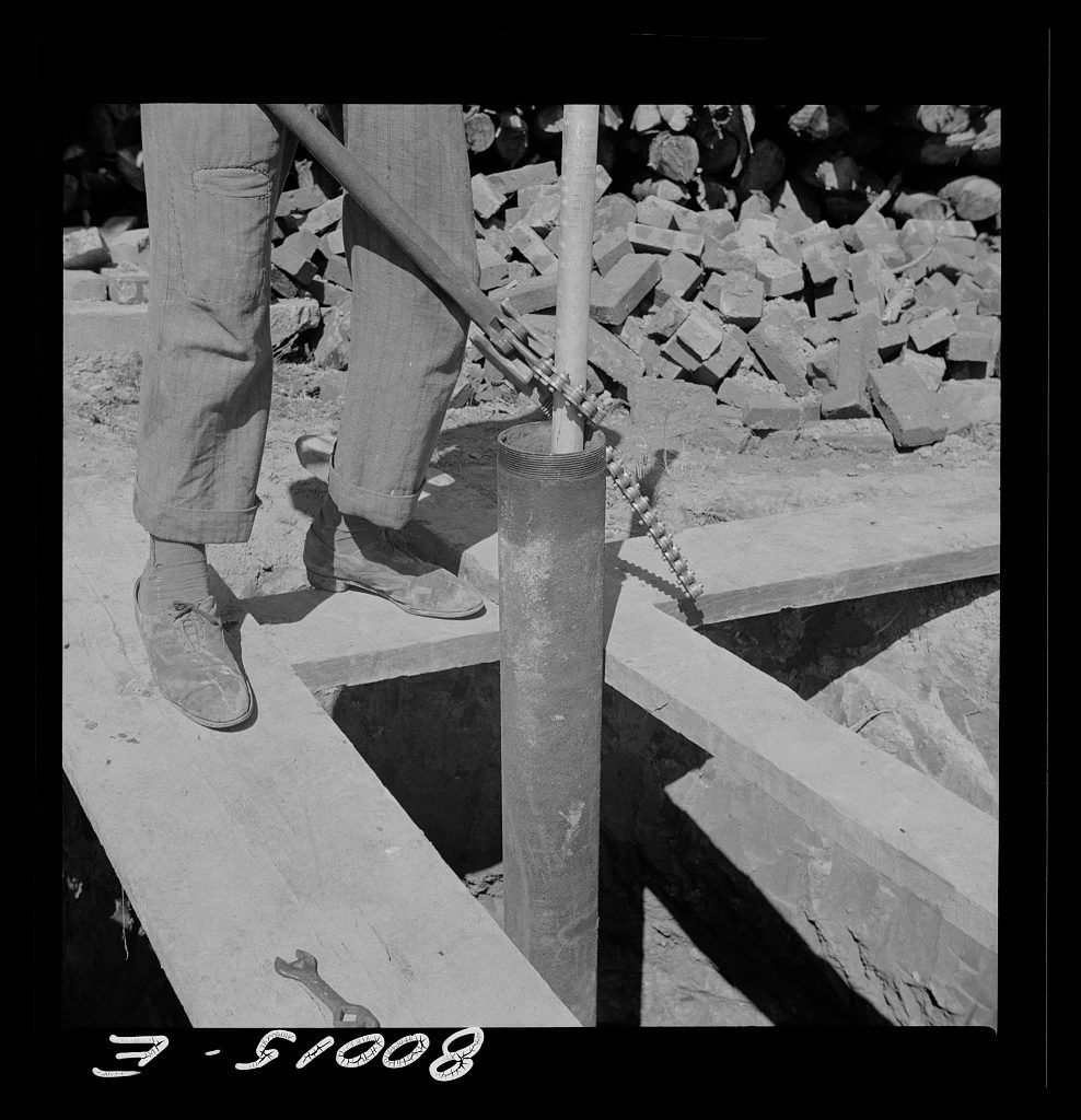 A worker using a pipe wrench during a well-drilling project in 1941