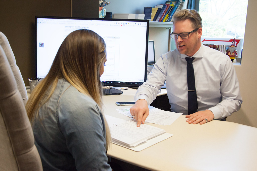 A professional reviewing a paper claim form with a client at a desk