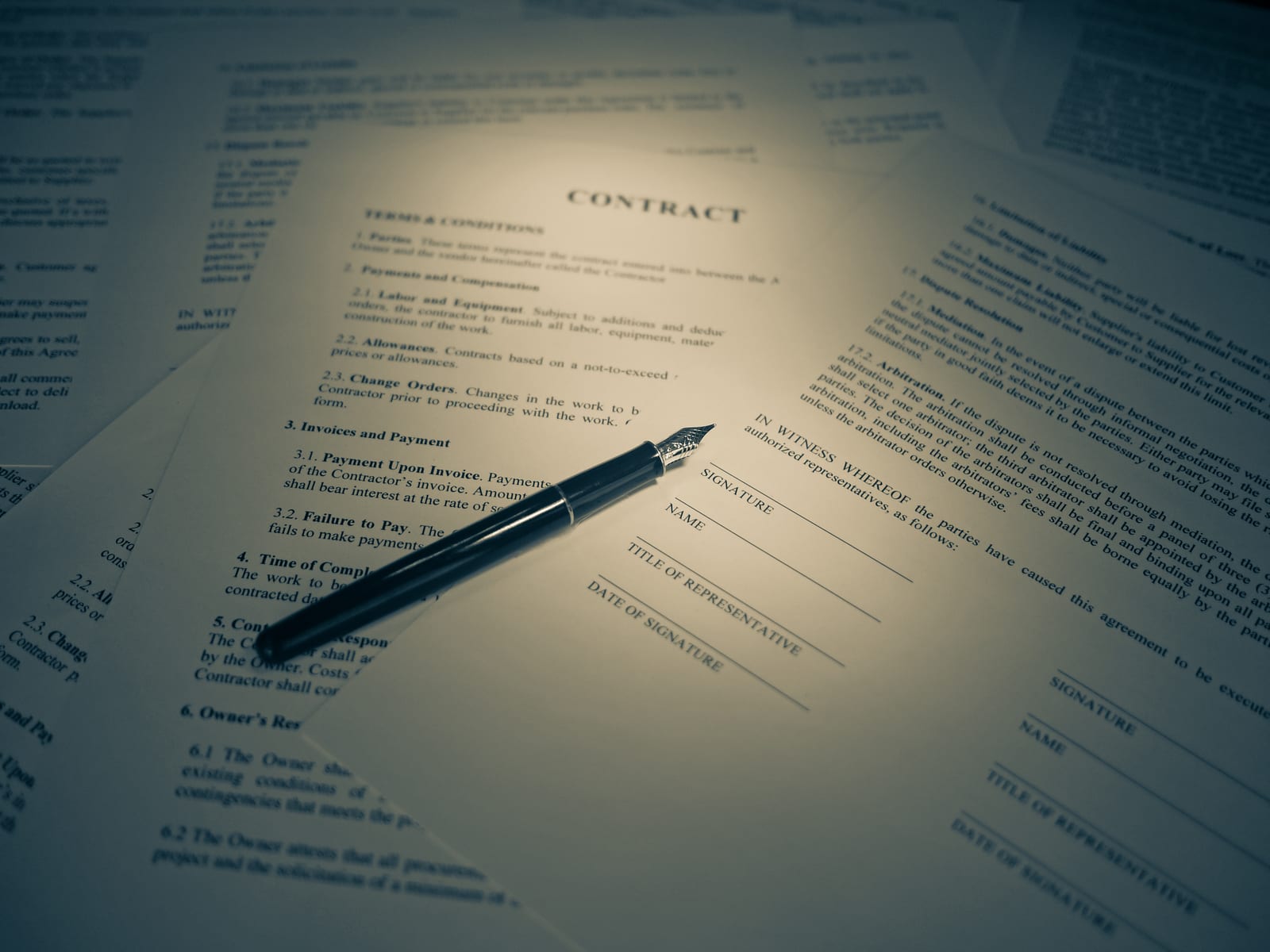 A printed contract document with signature lines and a fountain pen resting on top